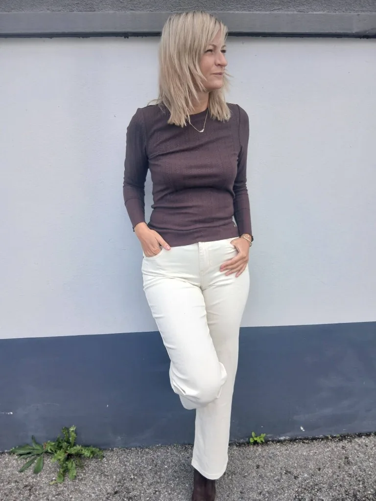 Laurie en haut côtelé chocolat et pantalon crème, les mains dans les poches, en bottines de daim